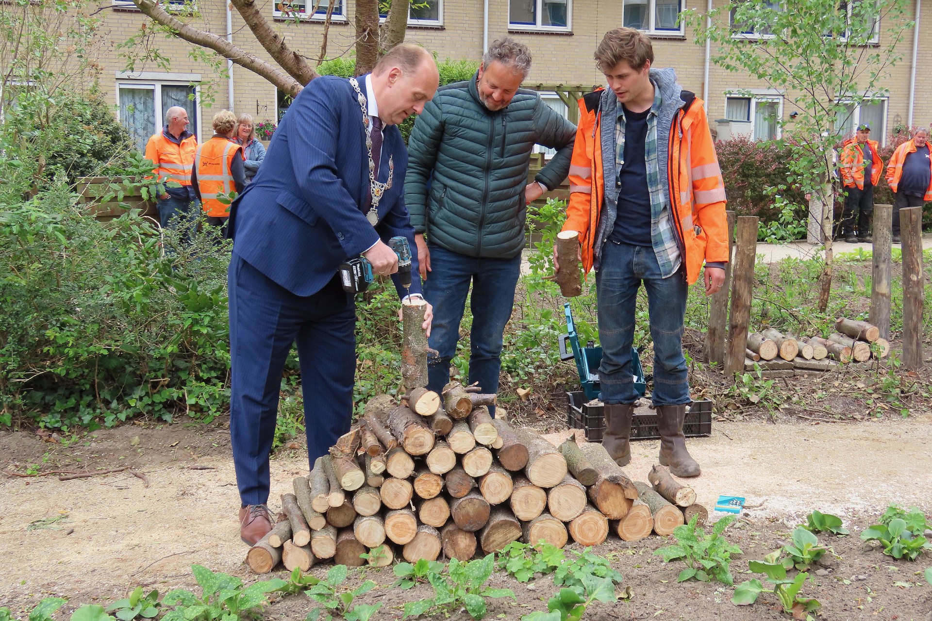 Burgemeester Frederik Zevenbergen boort  in een blok hout.