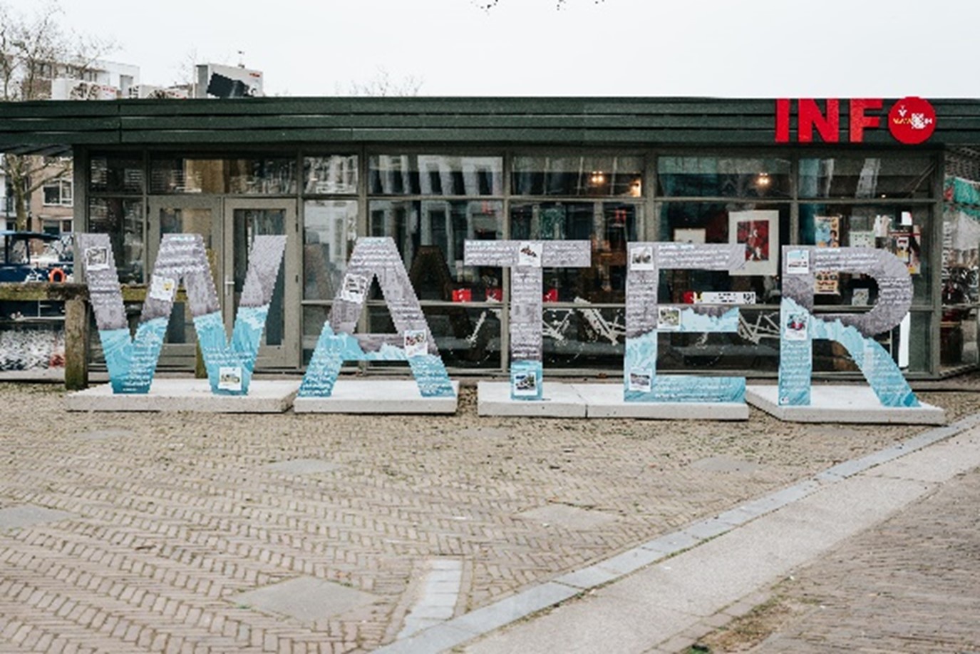 Reizende buitenexpositie WATER. Op de afbeeldingen zie je de letters W.A.T.E.R naast het infopunt van VlaardingeDoen op de Westhavenkade staan.