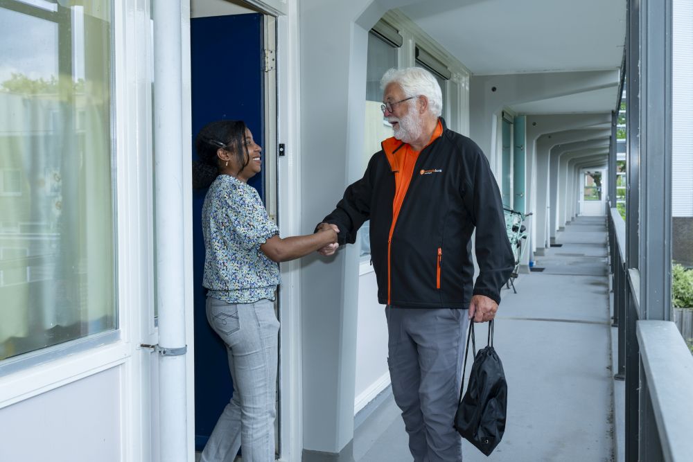 energie coach bij voordeur en geeft hand aan bewoonster