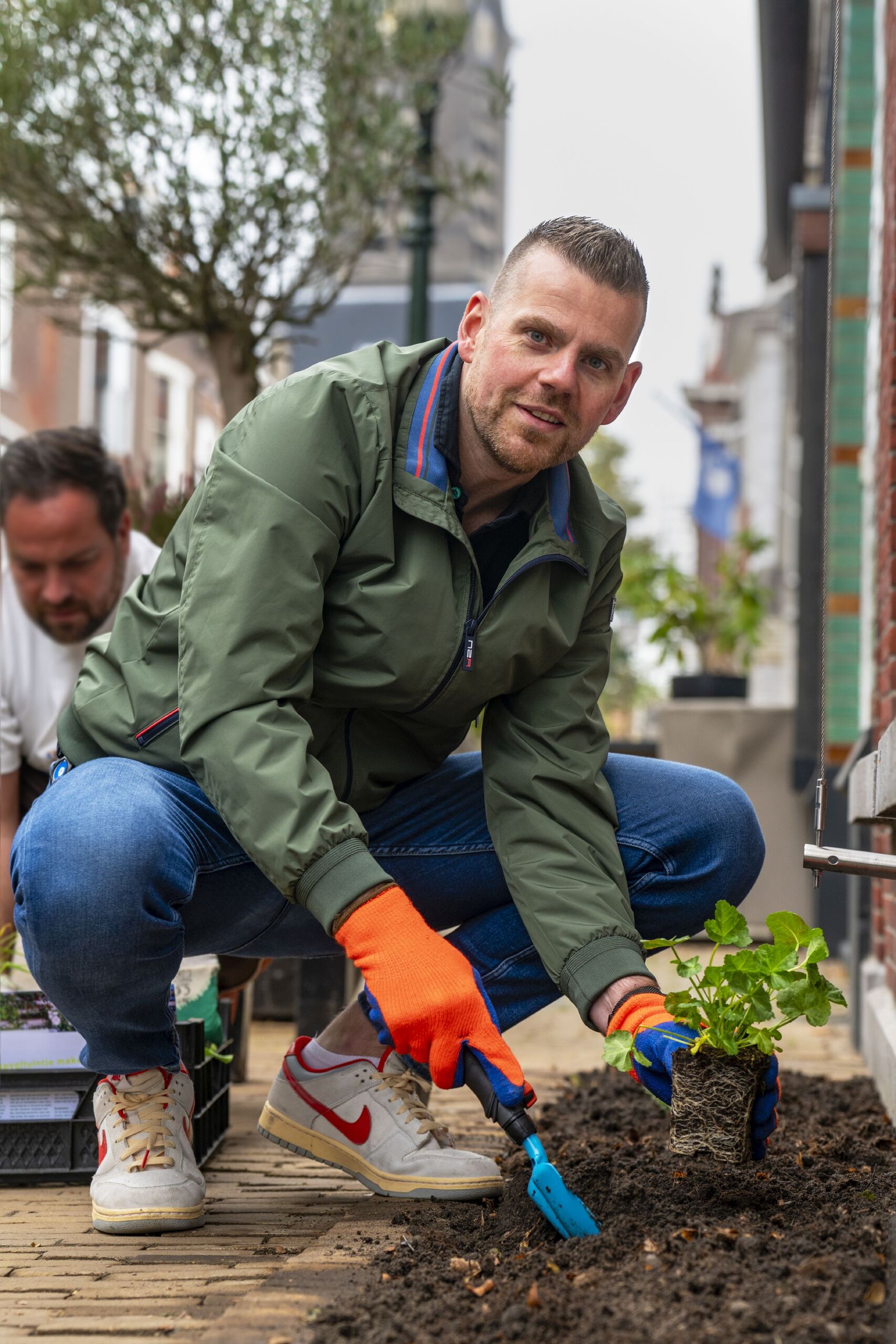 Wethouder Rens de Ron helpt mee met het aanleggen van een geveltuintje