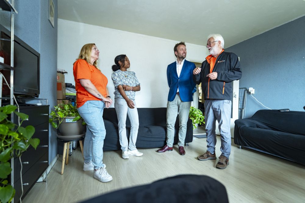 energie coach staat in een woonkamer met mensen te praten